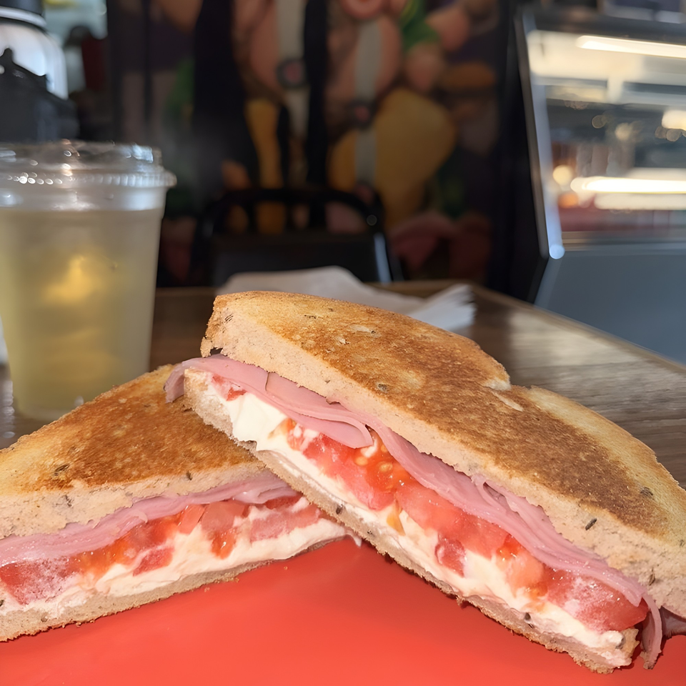 Toasted sandwich with ham, tomato, and cream cheese, served with a drink at Pom Pom's Teahouse.